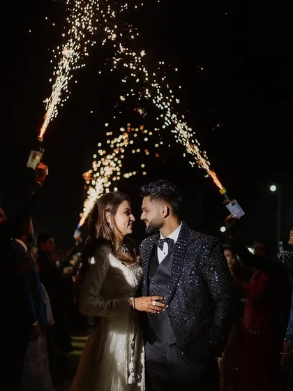 A grand entrance for the couple, surrounded by friends holding cold pyro sparklers. This creates a tunnel of light and celebration, making for an unforgettable start to their sangeet night.