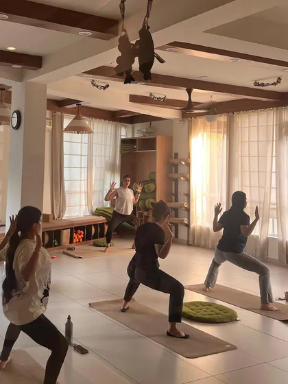 Students hold a powerful Goddess Pose, building strength in the legs and hips.