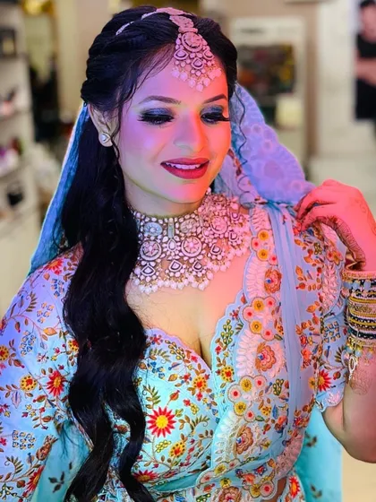 A beautiful client ready for a wedding event in a light blue floral saree. Her makeup features a dramatic blue smokey eye that complements her outfit perfectly, paired with an elegant hairstyle.