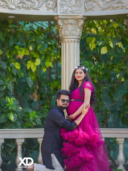 A classic pose with the partner hugging the mother-to-be from behind, both looking happy and relaxed.