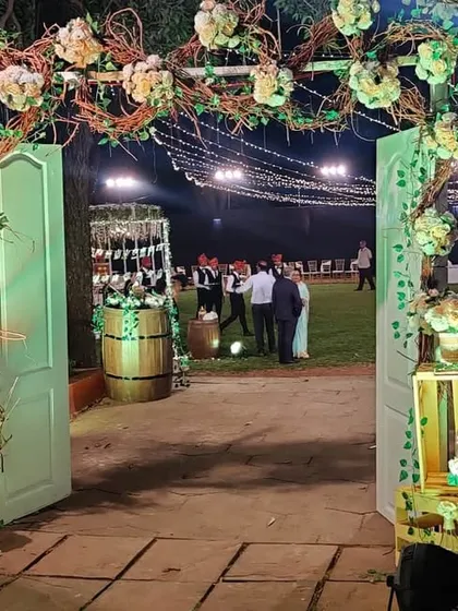 We created a warm and inviting rustic theme for this outdoor reception. The entrance features a personalized welcome sign, reclaimed wooden barrels, and an arch made of natural branches and white flowers, setting a charming tone for the event.