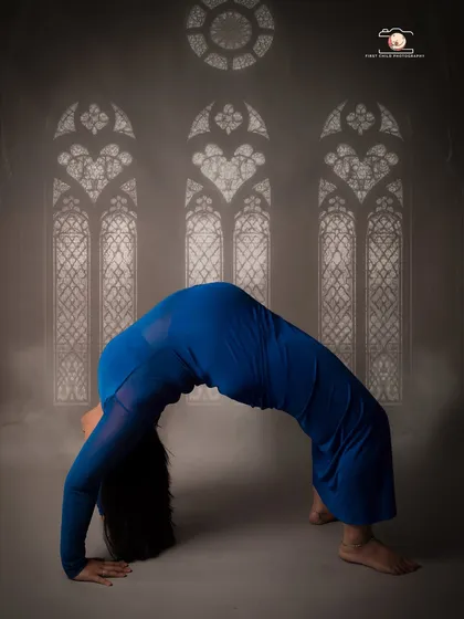 For mothers who find strength and peace in yoga, a prenatal yoga session can be a powerful way to document the journey. This image captures the beauty of the human form in a graceful wheel pose, set against an artistic backdrop.