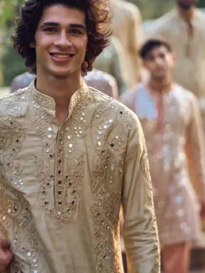 A close-up on a smiling model, highlighting the intricate mirror and threadwork around the collar.