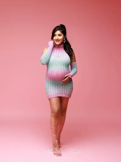 A fun and fashionable pose in a colorful knit dress, showing that maternity style can be playful and trendy.
