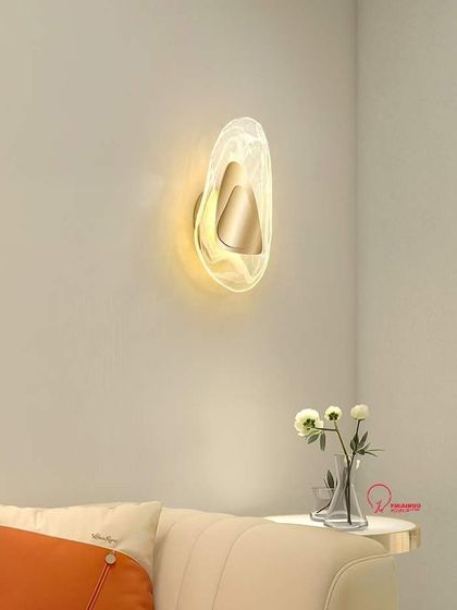 An organic-shaped wall sconce with a frosted acrylic finish. This light provides a soft, diffused glow, perfect for a serene bedroom setting.