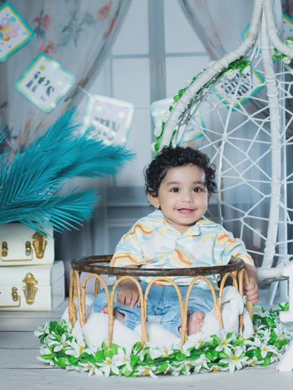 A beautiful half-birthday setup with a teal and white color scheme, complete with a cake and a hanging chair.