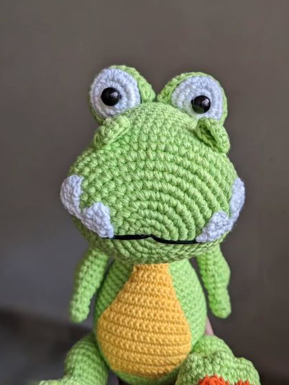 A close-up portrait of the happy dinosaur amigurumi.
