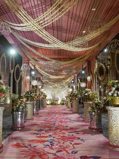 The full view of the magnificent pink floral entryway. The long carpet runner guides guests towards the main event space, building anticipation with every step.
