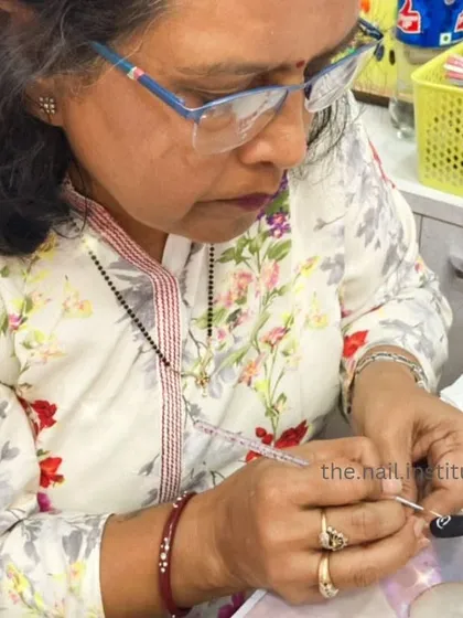 A student carefully paints a design on a practice wheel, surrounded by a variety of colors and tools.