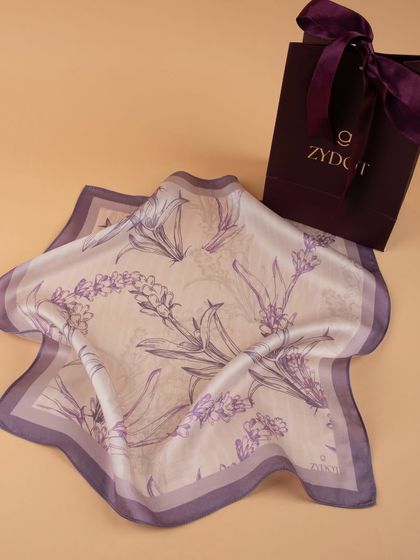 A lavender-themed pocket square with a floral print, displayed with its branded gift bag.