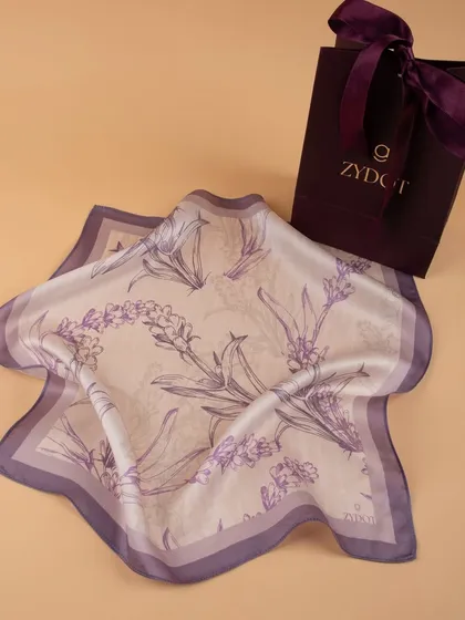 A lavender-themed pocket square with a floral print, displayed with its branded gift bag.