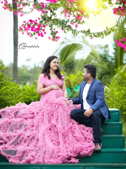 A romantic couple's portrait on green steps, surrounded by flowers. The mother-to-be's pink ruffled gown is simply stunning.