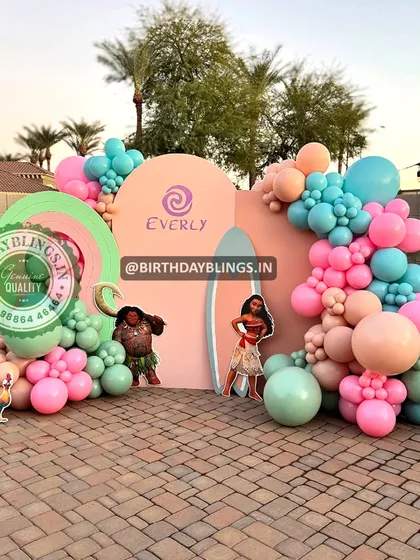 An outdoor Moana party with a pastel color scheme. The surfboard-shaped backdrop and palm tree cutouts create a fun, beachy vibe.