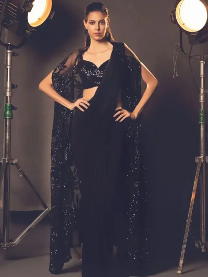 This all-black cape saree is the epitome of chic. The sheer, sequined cape adds a layer of drama and sophistication to the simple drape, creating a powerful and modern look.