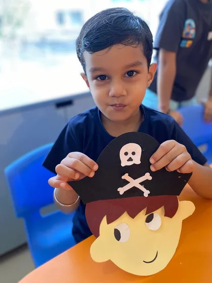 A proud student shows his completed pirate craft directly to the camera.