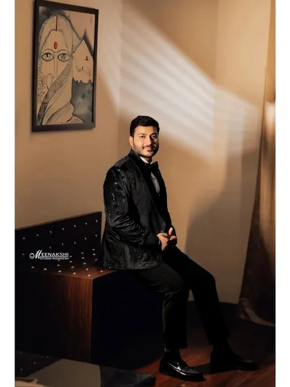 A full-length portrait of the groom seated, captured with creative lighting that casts artistic shadows. This adds a touch of drama and sophistication to the gallery.