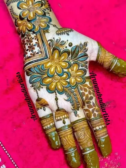 A vibrant and colorful design, showing the fresh green henna paste. This floral pattern with hanging jhumkas is a fun and festive choice for any occasion.
