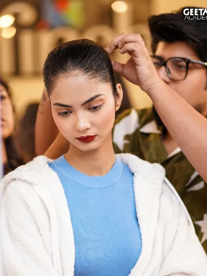 A student works on a model's hair backstage. These opportunities are crucial for building a professional portfolio and making industry connections.