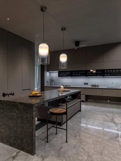 Set in an Ahmedabad farmhouse, this kitchen has a soft monolithic feel. Floor-to-ceiling cabinetry in Calgary Laminate and a sculpted dark stone island create a sense of weight and clarity.