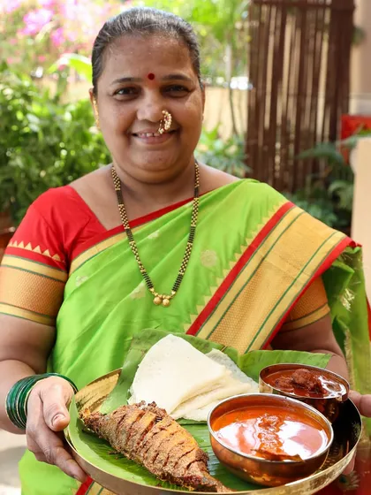 A portrait of a home chef proudly presenting her Malvani fish thali, capturing the love and tradition behind the food.
