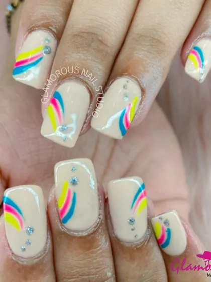 A playful design on a nude base, this look features a rainbow-like arc of blue, pink, and yellow, accented with tiny rhinestones.