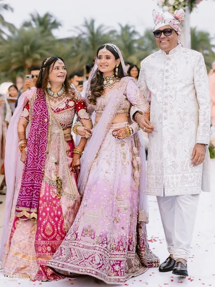 A proud father and mother walk their daughter down the aisle at her beach wedding in Goa, a moment filled with love and emotion.