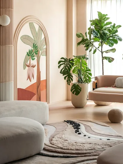 The hand-painted mural, framed by a soft arch, serves as a beautiful backdrop in this calm living space. We layered the home with lush greenery to honor the clients' love for nature, infusing every corner with life.