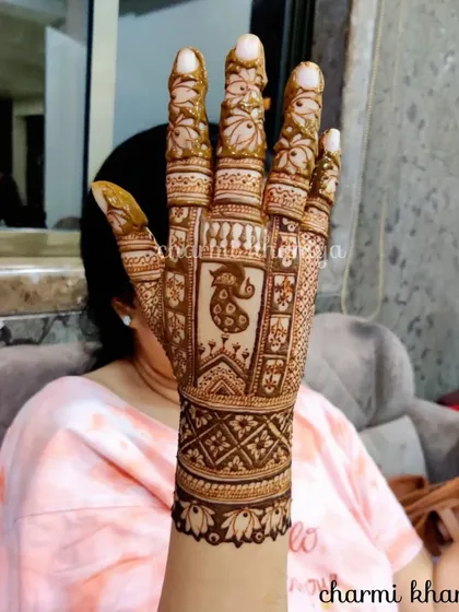 A lovely back-of-hand design featuring a peacock. The pattern extends up the arm with traditional motifs, making it perfect for showing off at a sangeet or wedding.