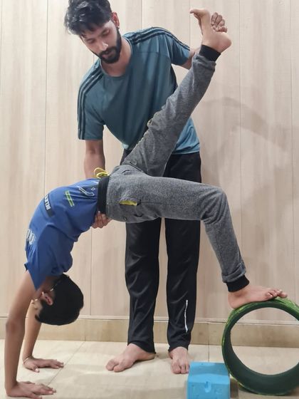 This image captures the focus and determination of our young students. With instructor support, this child is working on a challenging backbend variation, developing both physical and mental resilience.