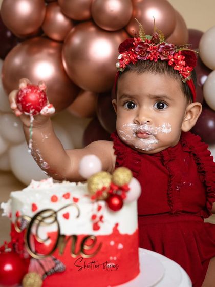 She's got her hands on the cake topper! A fun, candid moment from the first birthday celebration.