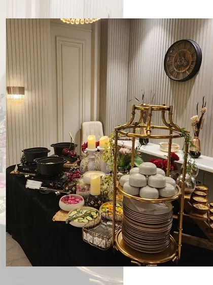 An elegant buffet setup for a Diwali house party. The black and gold theme with candles and a tiered platter creates a sophisticated and festive atmosphere.