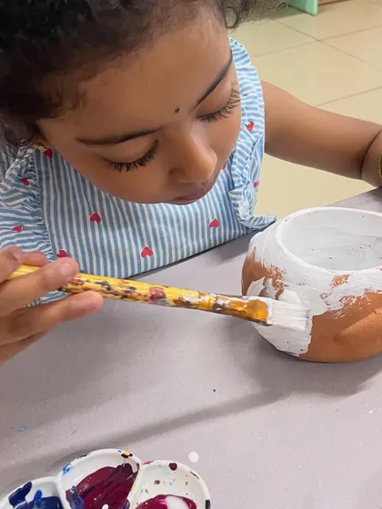 The first step in planter painting is applying a solid base coat of white paint, as this little artist demonstrates.
