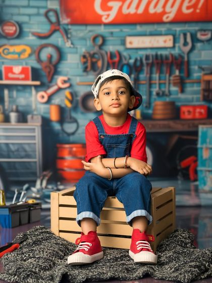 The boss of the garage. This little boy in his denim overalls and backwards cap has the perfect cool and confident pose for this fun themed shoot.