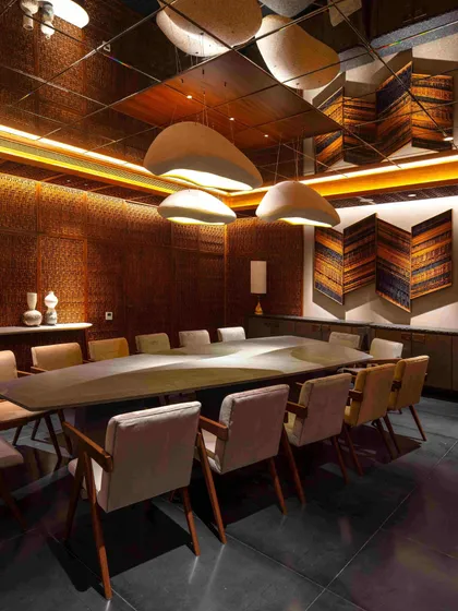 A mirrored ceiling reflects the dramatic dining setting in the Bammi Residence. The design uses reflection to expand the sense of space in a room with no natural light.