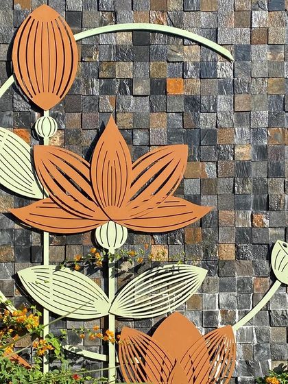 A close-up of the lotus art installation. This piece pays homage to the lotus as a symbol of beauty and prosperity, with its delicate metal forms set against a rustic, textured stone wall.