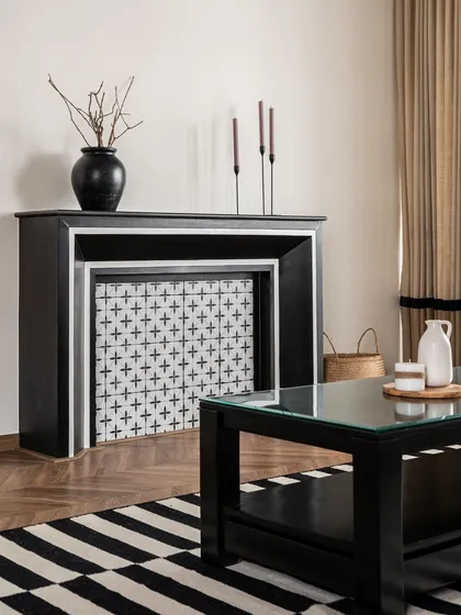 A custom-designed faux fireplace serves as a charming focal point, featuring patterned tiles that echo the staircase design. This element adds a touch of classic European character to the living space.