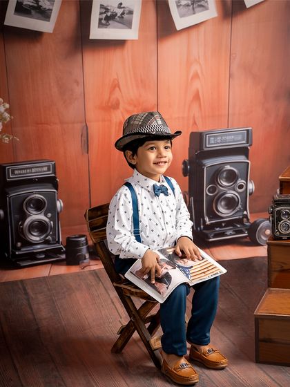 A classic portrait in a retro setting. This little boy, dressed in a bow tie and fedora, looks like he's stepped out of another era in our vintage camera-themed studio.