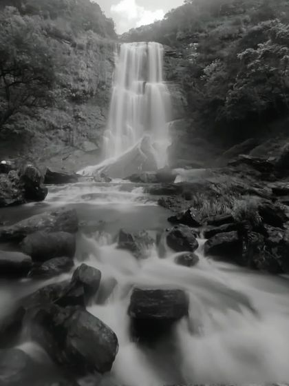 A dramatic black and white long-exposure shot of a waterfall.