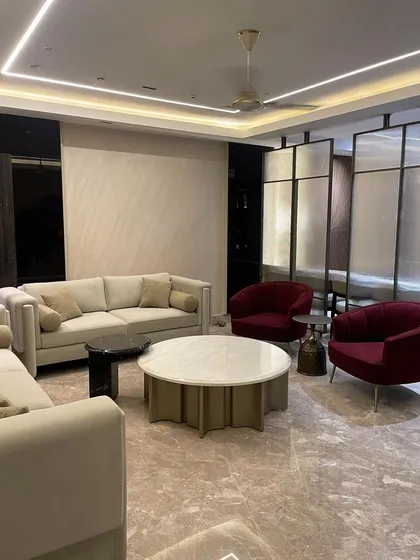 We designed this contemporary living room to feel luxurious and inviting. The centerpiece is a custom Italian stone coffee table, complemented by deep red accent chairs that add a vibrant pop of color. The large nine foot sofa, upholstered in soft suede velvet, offers ultimate comfort.