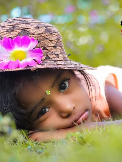 A pensive and sweet moment during an outdoor photoshoot. Lying in the grass with a cute hat, this little girl's thoughtful expression makes for a beautiful and quiet portrait.