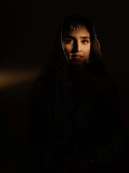An intense and captivating low-key portrait. With only a sliver of light on her face, this image is mysterious and artistic, showcasing our ability to create fine art wedding photography.