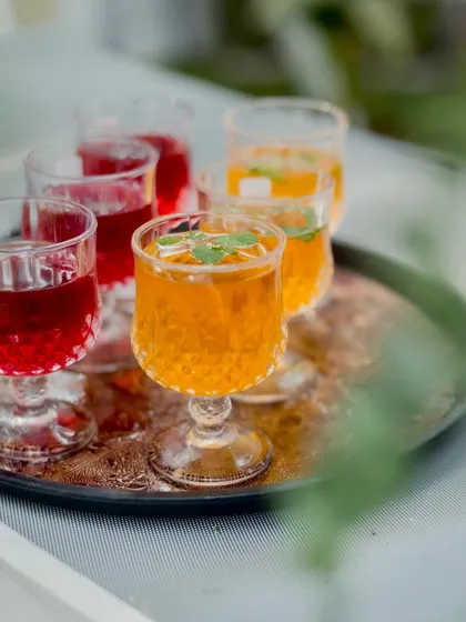 A tray of my special mocktails, including the deep red Kokam Kala Khatta and a golden ice tea. These drinks are served in elegant glassware, adding a touch of class to the refreshment counter.