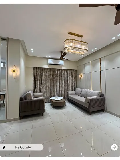 This living room exudes subtle luxury with its neutral-toned sofas, elegant crystal chandelier, and minimalist wall paneling. The design creates a calm and sophisticated atmosphere.