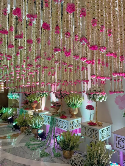 Strings of tradition, shades of celebration. This entrance, with its canopy of hanging flowers and beautifully arranged decor tables, is pure floral magic. 🩷🌸