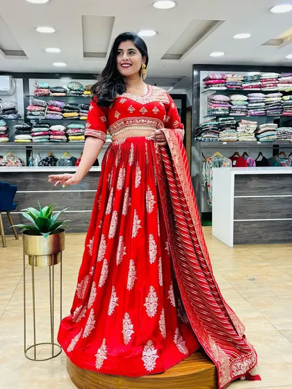 A stunning red Anarkali-style lehenga, perfect for making a statement. The intricate silver work and flowing silhouette make it a royal choice for any grand occasion.