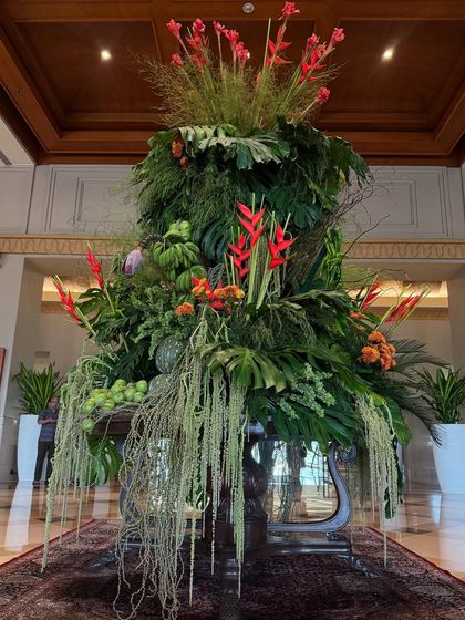 A breathtaking arrangement of lush green foliage graces the lobby, bringing a sense of tranquility and natural beauty. The pops of red and the cascading form make it a true statement piece.
