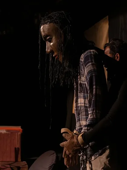 A giant puppet of Gulliver, bound in chains, looks on with a somber expression. This scene from 'Gulliver's Travel' captures the moment he is held prisoner by the tiny Lilliputians.