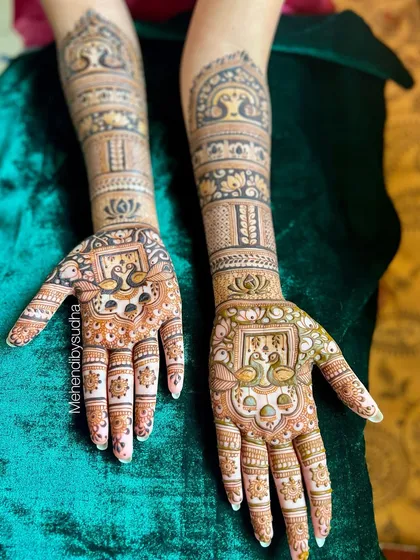 A beautiful engagement design with peacocks framed in a jharokha on the palms, and lotus motifs on the arms.