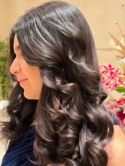 A side view of expertly styled curls. The soft volume and face-framing layers create a look that is both glamorous and sophisticated.