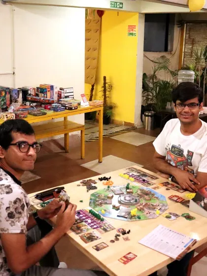 Two players are deep in thought during a game of 'Viscounts of the West Kingdom'. My cafe welcomes both casual players and serious board game enthusiasts.